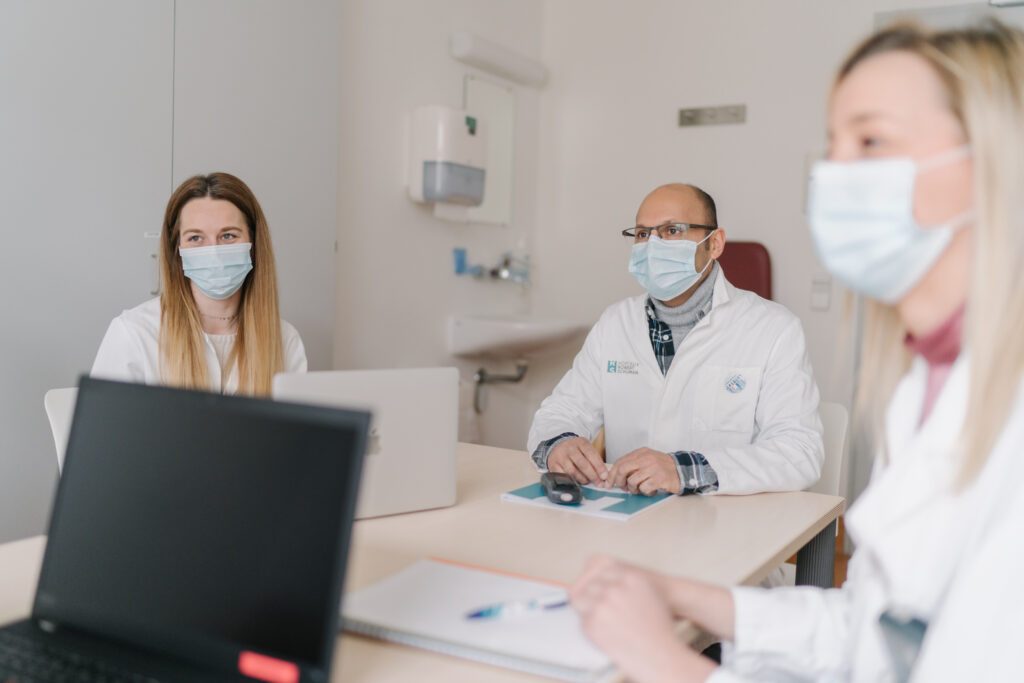 Foto eines Steffmeetings mit 3 Pflegekräften, die gemeinsam an einem Tisch diskutieren
