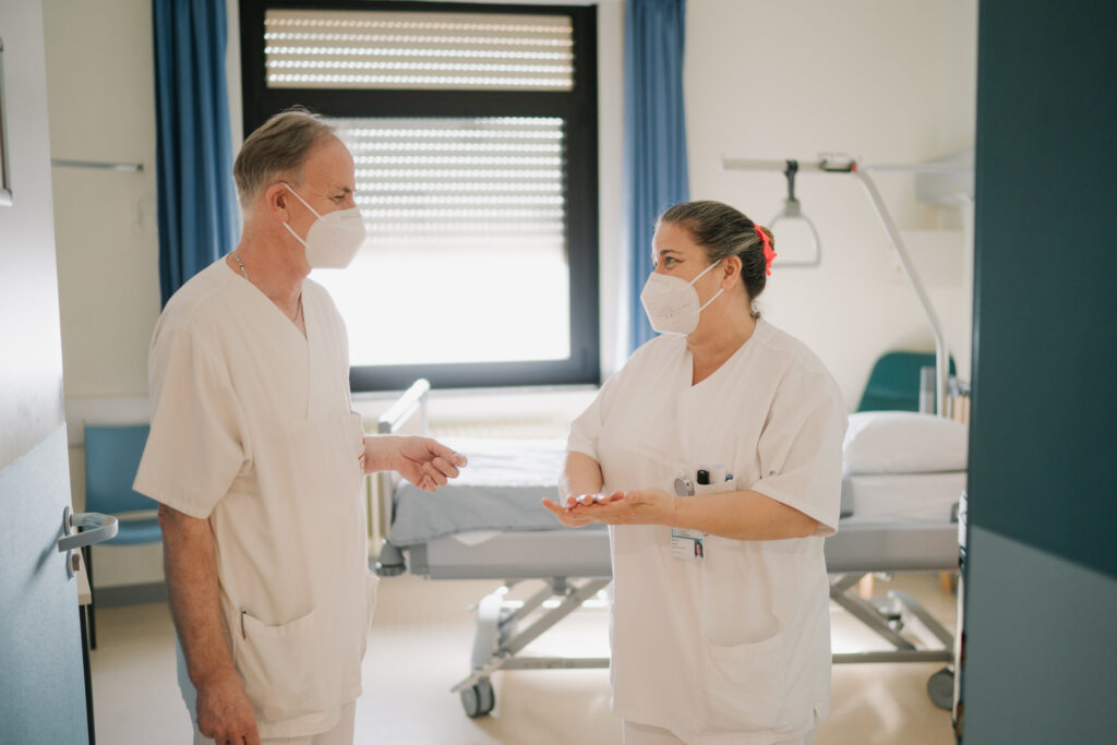 Foto von zwei Patienten, die sich am Eingang eines Patientenzimmers miteinander unterhalten (Zithaklinik)