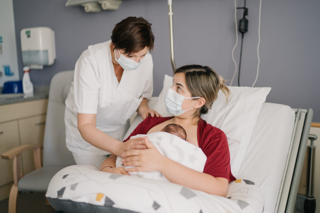 Foto einer Hebamme im Zimmer mit einer Mutter und ihrem Neugeborenen (Bohler-Klinik)