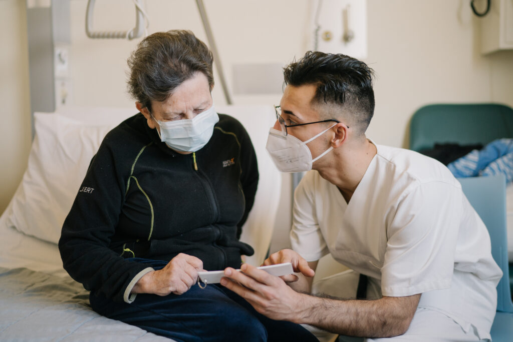 Foto eines Pflegers, der seinem männlichen Patienten die Schmerzskala zeigt (Hôpital Kirchberg)