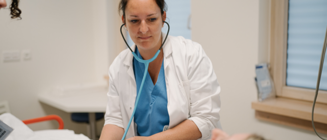 Photo d'une médecin avec un sthétoscope en train d'examiner un patient
